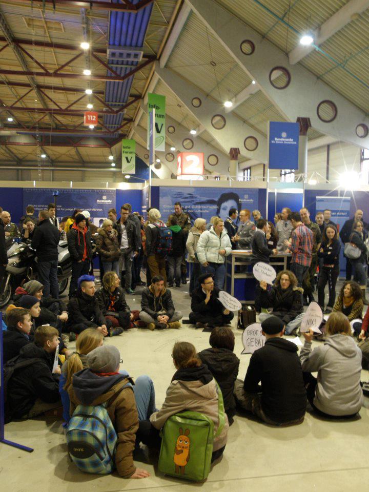 30 bis 40 junge KriegsgegnerInnen protestieren mit einem Flashmob und einem Die-in bei der Messe Jobs for Future am 22.2.13 in Mannheim gegen den Bundeswehrstand und seine Rekrutierungsaktivitäten.